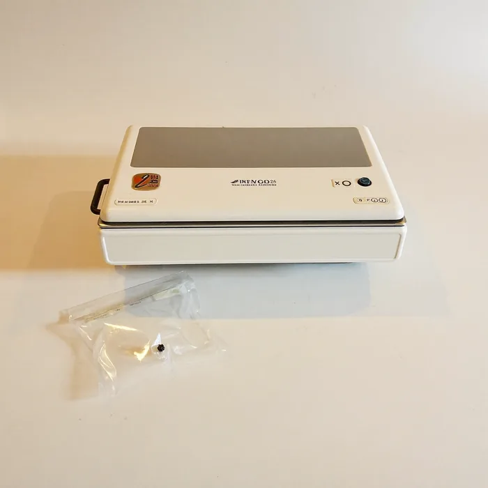 A countertop vacuum food sealer with a clear vacuum bag beside it